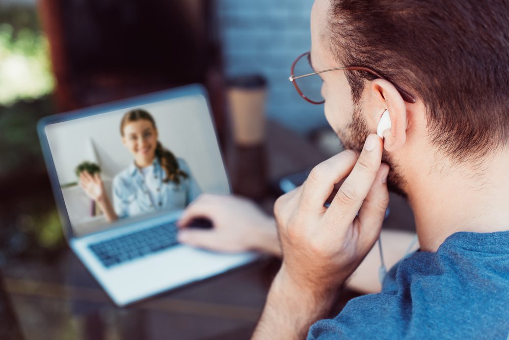 A man is listening to a video call on his laptop.