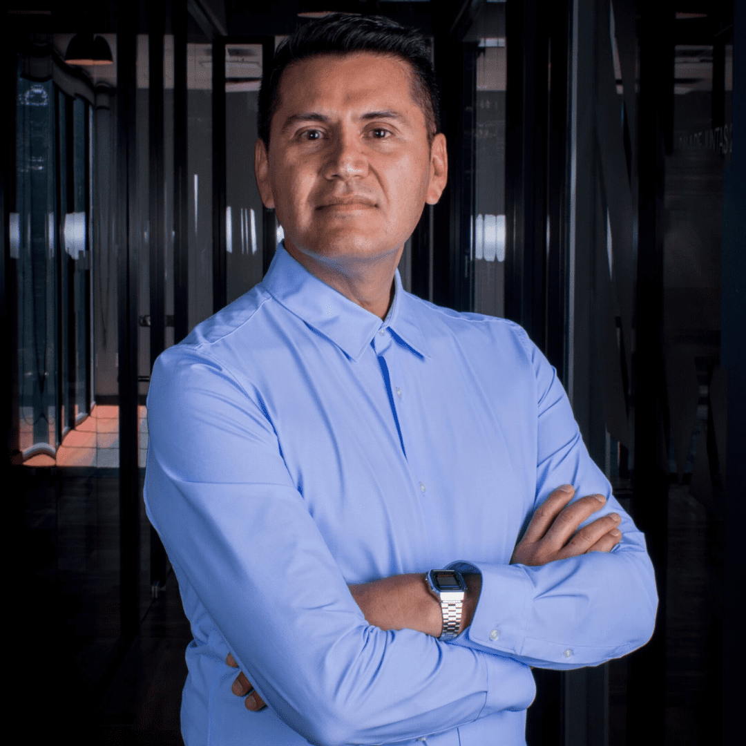A man in a blue shirt standing with his arms crossed.