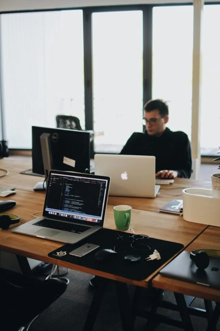 A group of people working at a desk with laptops.